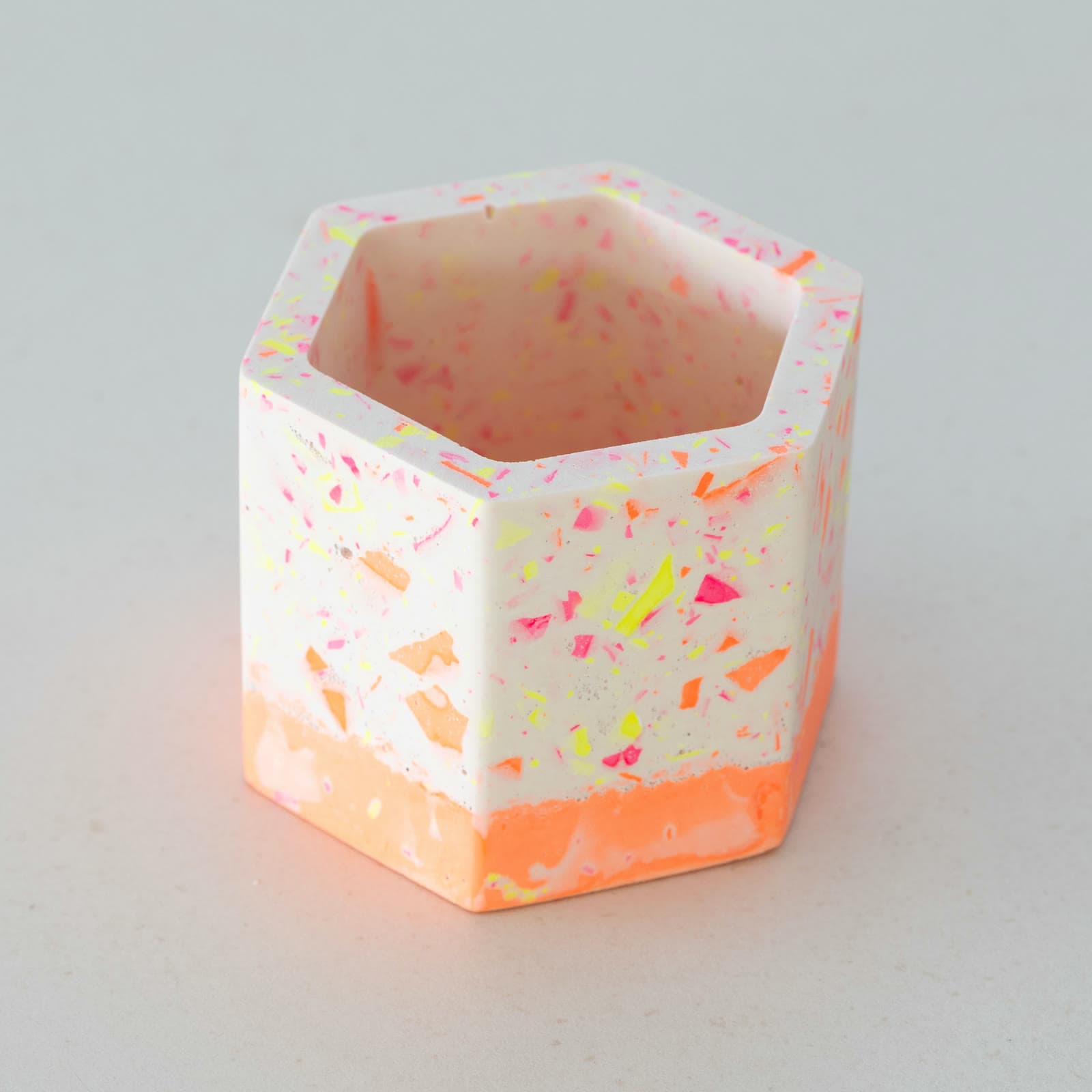 Zeshoekig wit terrazzo bloempotje met fluoroze, fluogele en oranje spikkels en een oranje onderrand