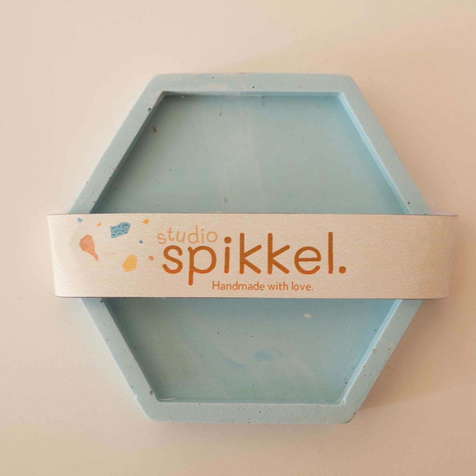 Zeshoekig lichtblauw schaaltje van gips met een Studio Spikkel-verpakkingsband