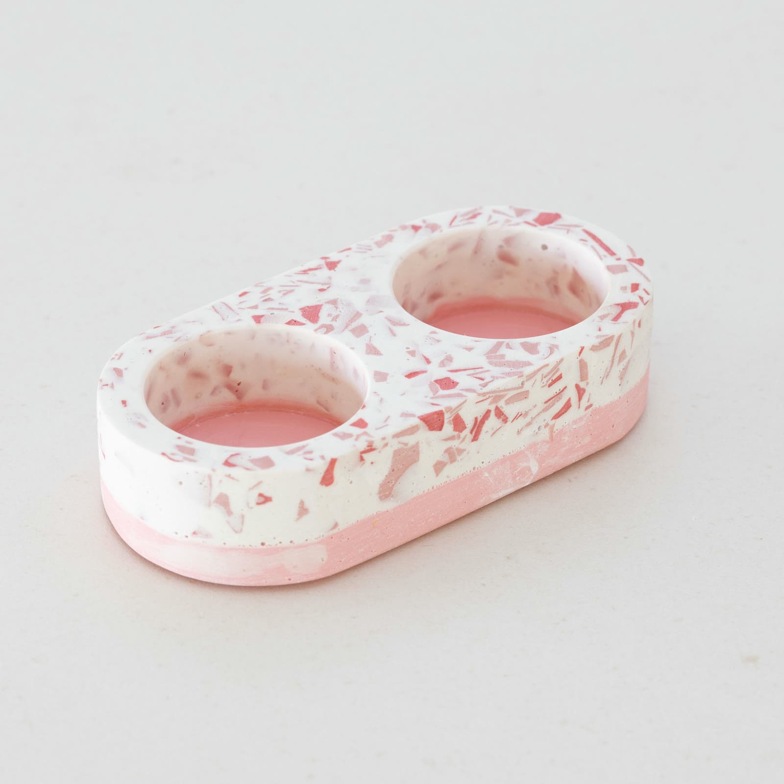 Witte terrazzo houder voor twee theelichtjes met roze en rode spikkels en een roze onderlaag