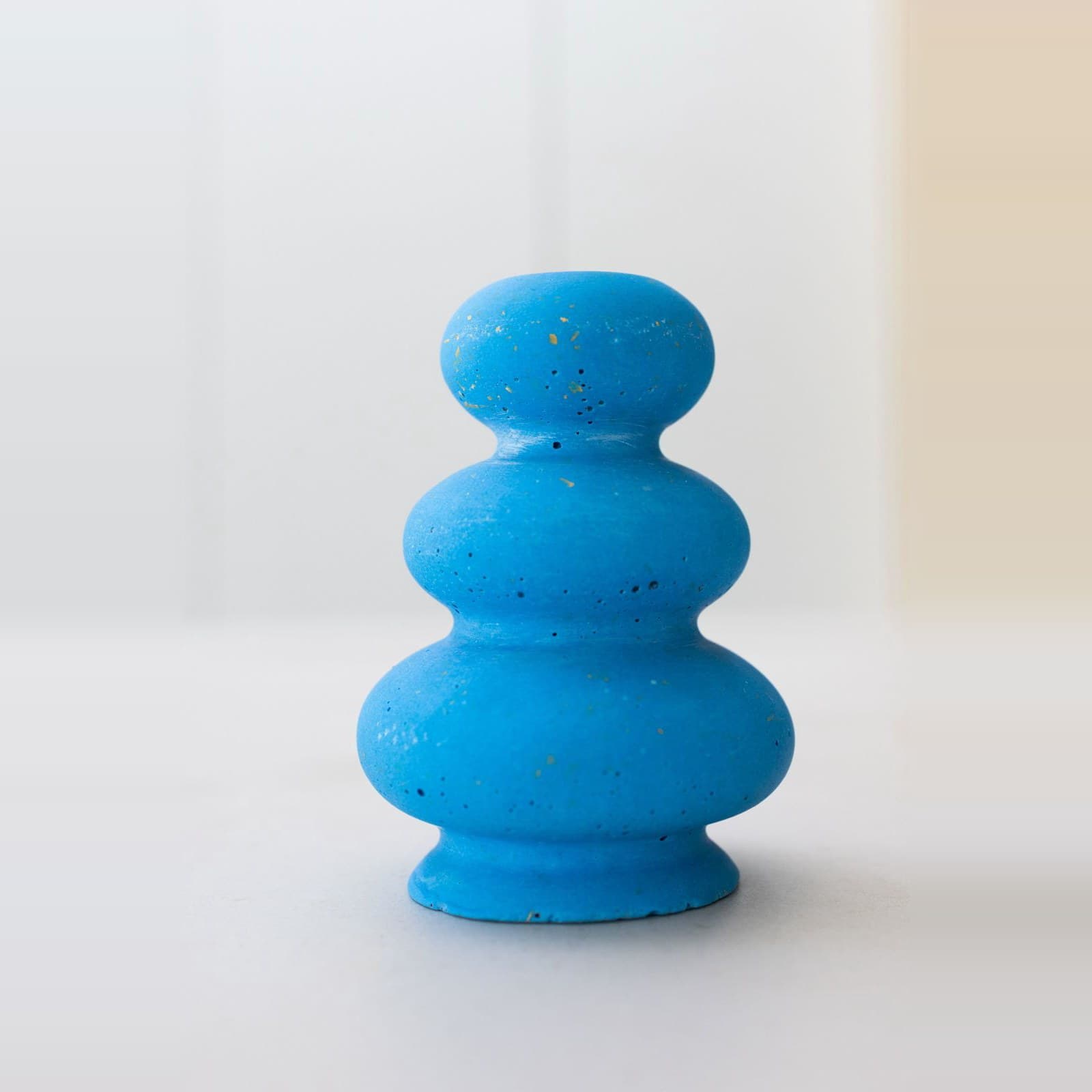 Felblauwe terrazzo kandelaar in drie ronde lagen op een smalle voet, met fijne okergele spikkels