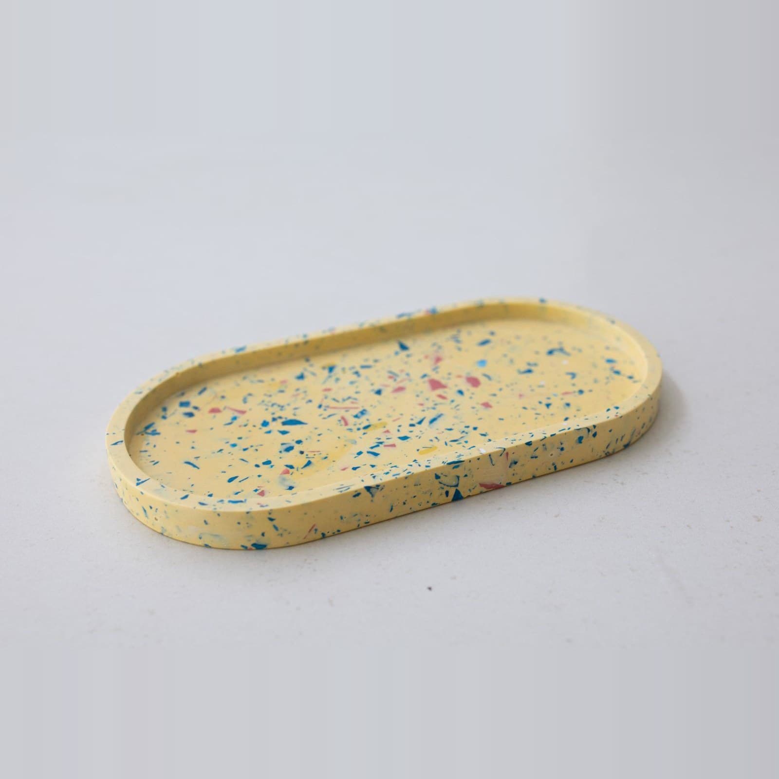 Ovaal zachtgeel terrazzo schaaltje met blauwe en roze spikkels, schuin van opzij