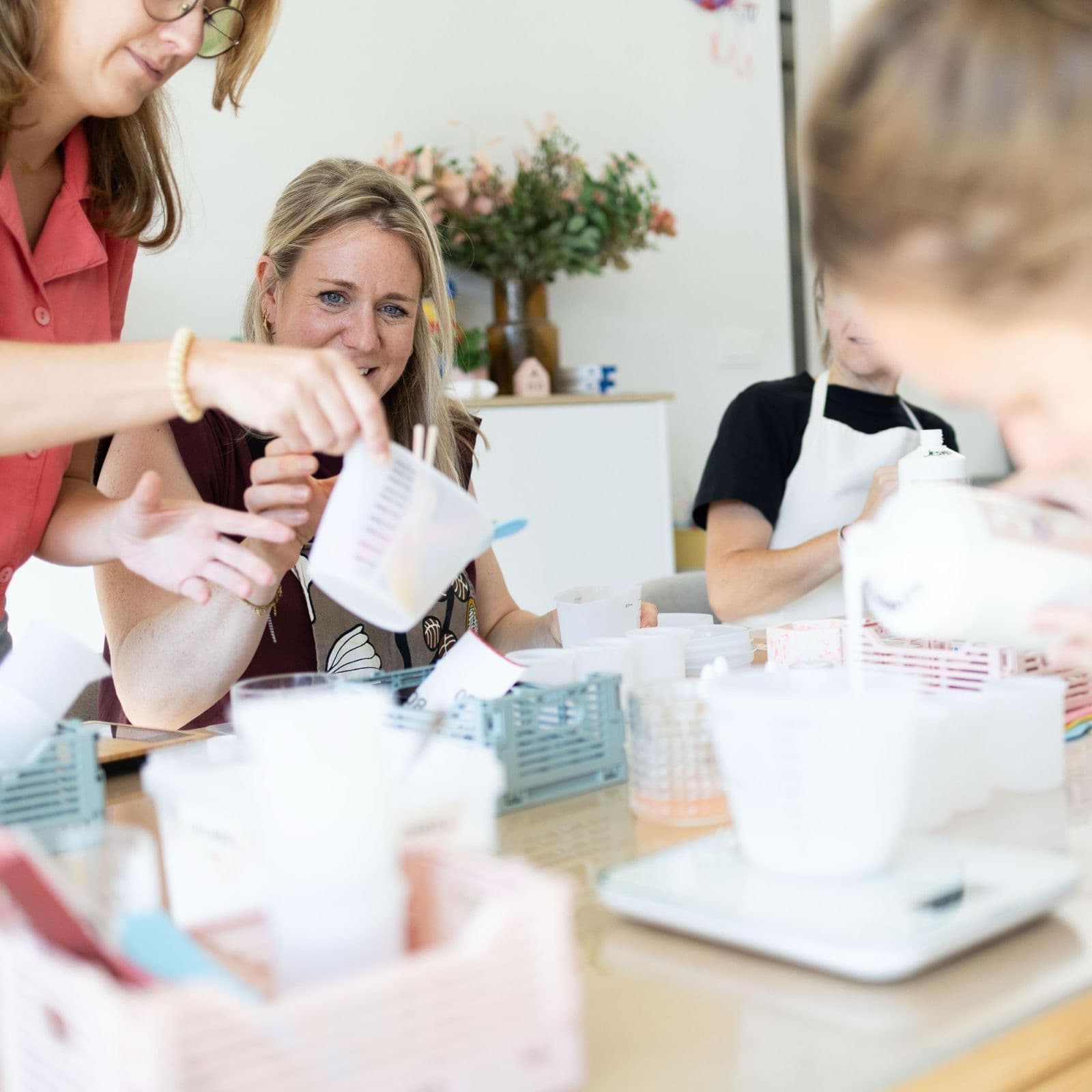 Een maker helpt een deelnemer met gieten uit een maatbeker